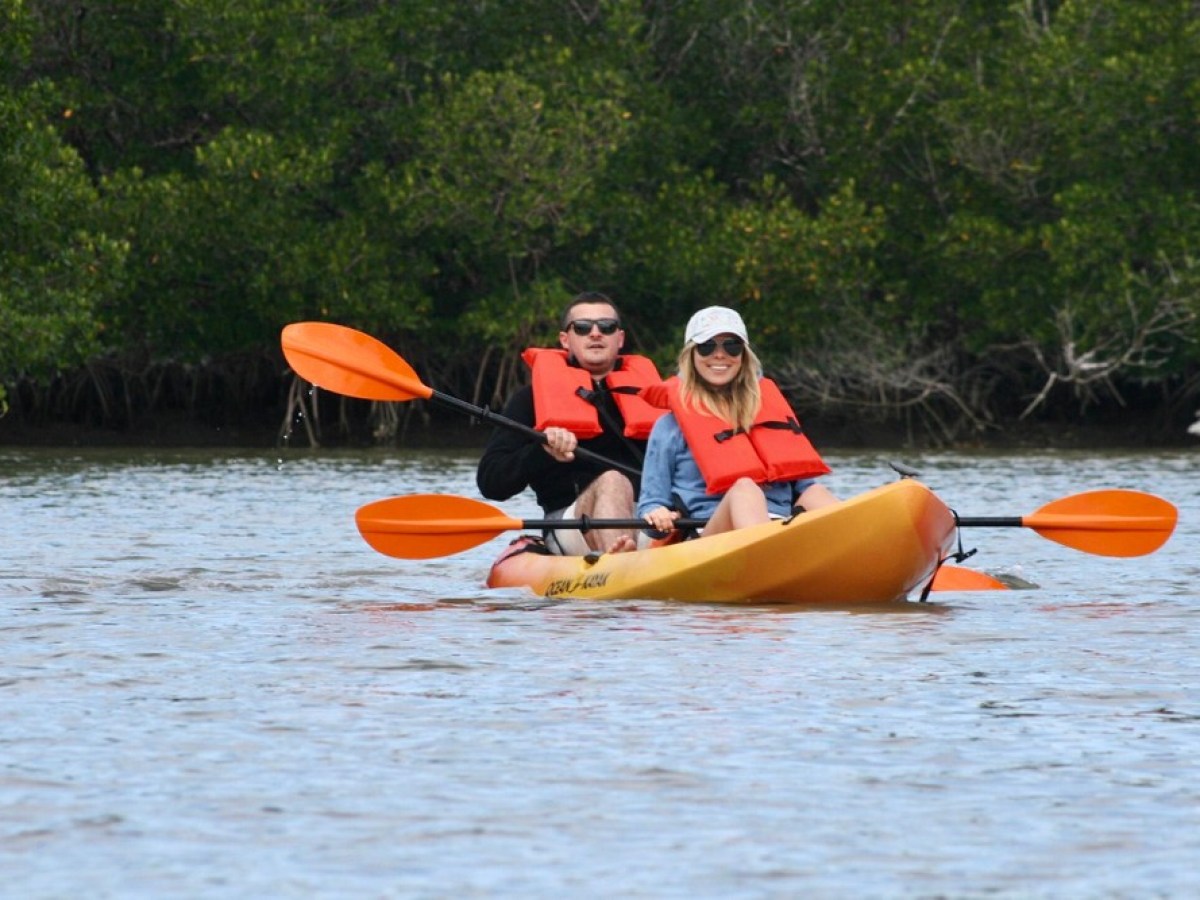 a man riding on the back of a boat next to an orange frisbee