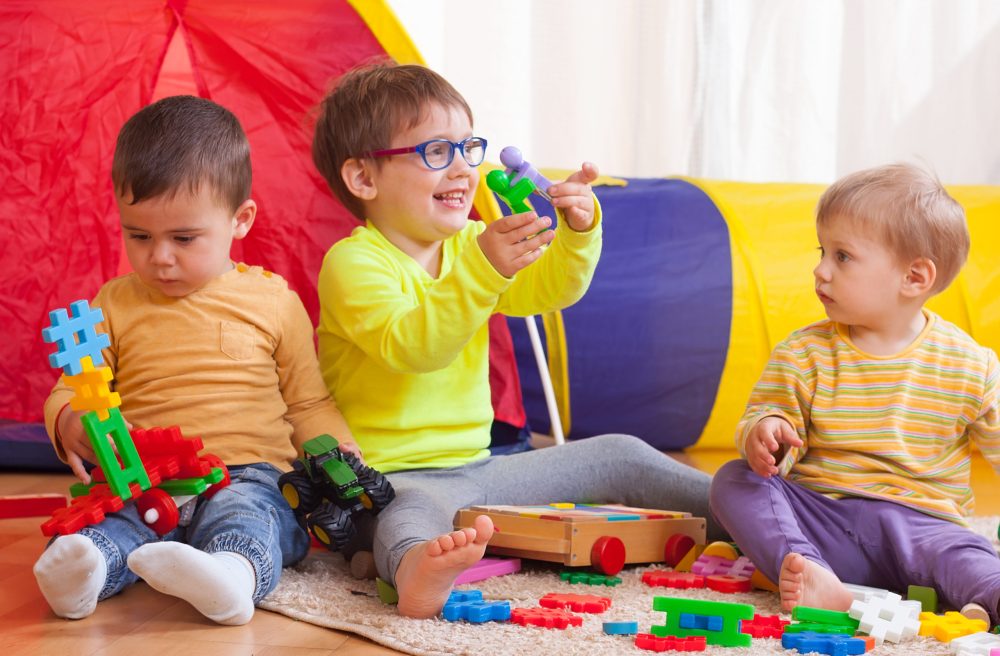 Two girls and boy with toys on floor at home